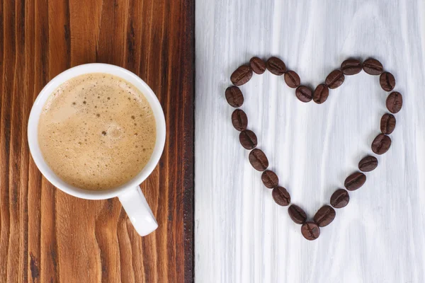 El café y el corazón de los granos de café sobre la superficie de madera —  Fotos de Stock