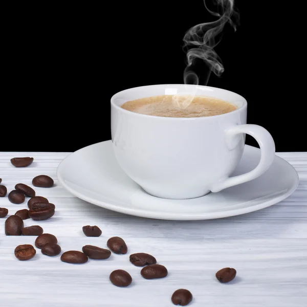 Café caliente con humo y granos de café sobre mesa de madera —  Fotos de Stock