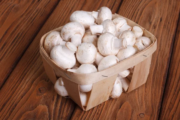 Champignon mushrooms in a basket on a wooden table. close-up — Stock Photo, Image