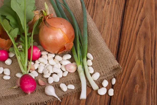 Onion, radishes, beans, garlic on a wooden table — Stock Photo, Image