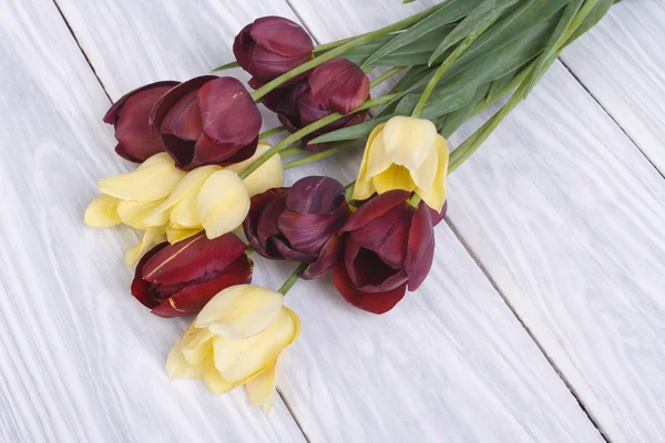 Ramo de tulipanes amarillos y rojos sobre una mesa de madera —  Fotos de Stock