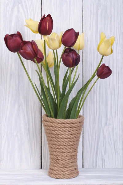 Strauß verschiedenfarbiger Tulpen in einer Vase auf einem hölzernen — Stockfoto