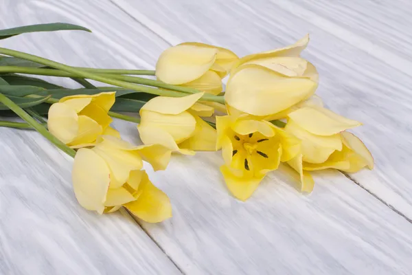 Ramo de tulipanes amarillos sobre una mesa de madera —  Fotos de Stock