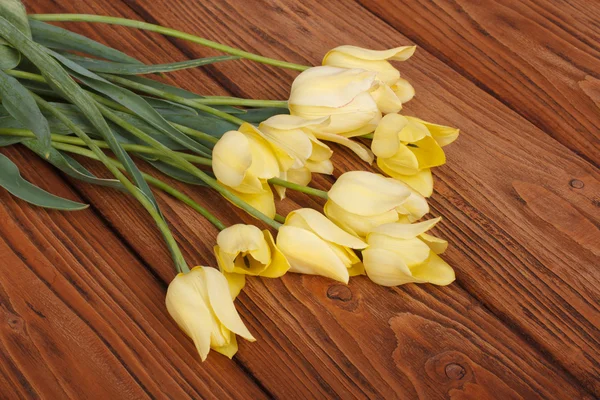 Boeket Gele tulpen op een bruine houten bord — Stockfoto