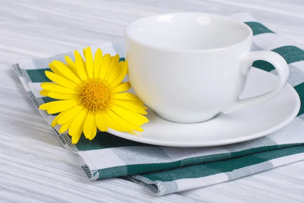 Taza blanca y platillo con ramo de margaritas sobre una mesa de madera —  Fotos de Stock