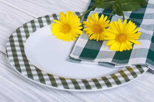 Зеленая тарелка и букет маргаритки на деревянном столе — стоковое фото