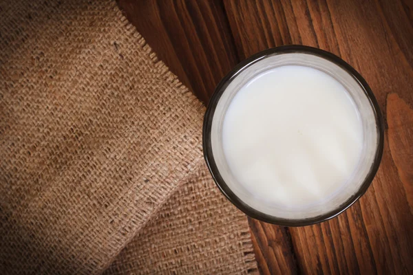 Milch im Glas auf einer Holztischplatte — Stockfoto