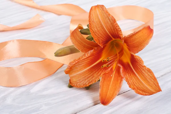 Lily flor com fita laranja em uma mesa de madeira — Fotografia de Stock