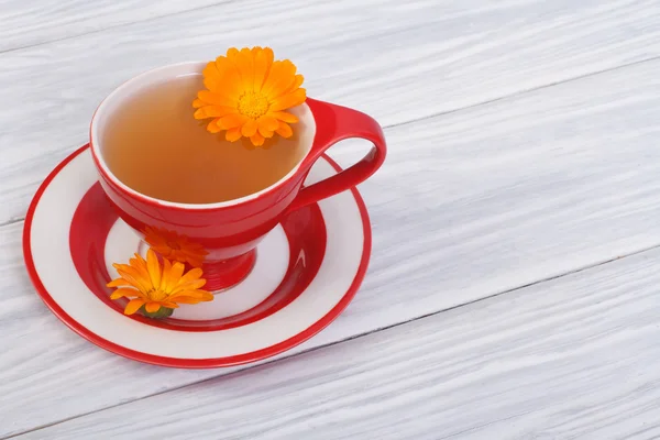 Herbal tea with calendula flowers in a red cup — Stock Photo, Image