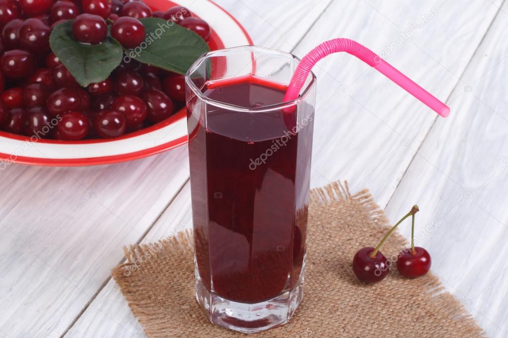Glass of cherry juice and plenty of ripe cherries on the table