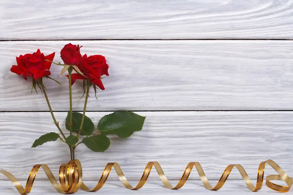 Rose red with gold ribbon. Floral frame on a wooden background — Stock Photo, Image