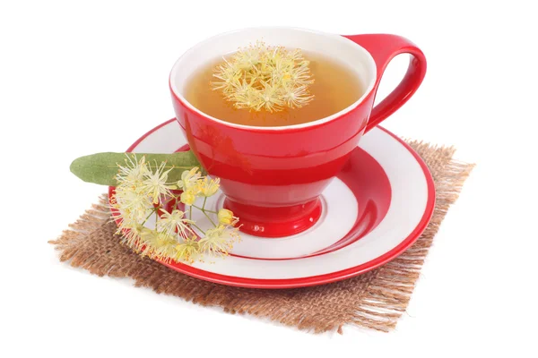 Thee met een linden in een rode kop op een servet geïsoleerd op wit — Stockfoto