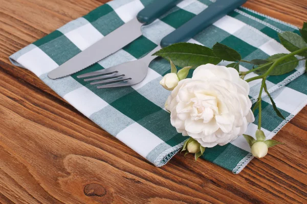 Cutlery knife and fork and a white rose on a napkin — Stock Photo, Image