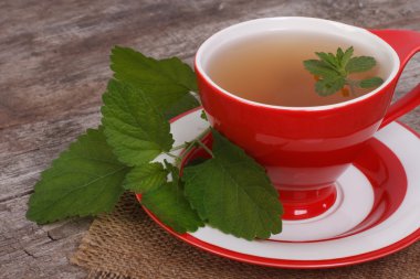 eski ahşap masa üstünde kırmızı bir fincan nane çayı