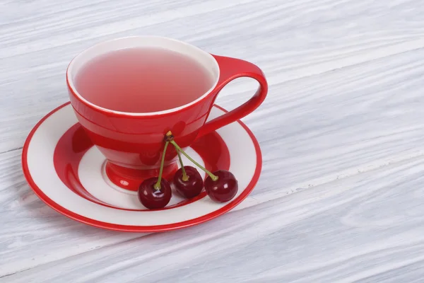 Té de frutas con cerezas de bayas en una taza roja —  Fotos de Stock