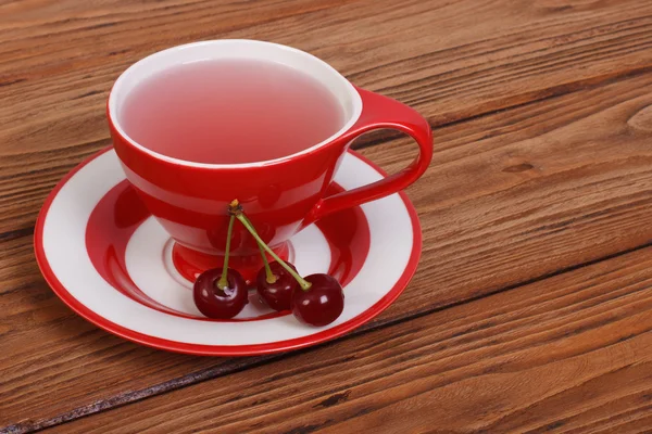 Ovocný čaj s třešňový plody na hnědý dřevěný stůl — Stock fotografie