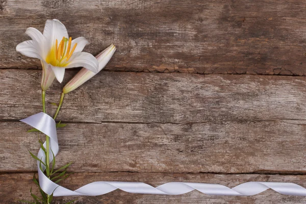 Blumengestell aus duftenden weißen Lilien mit einer Schleife auf einem hölzernen — Stockfoto