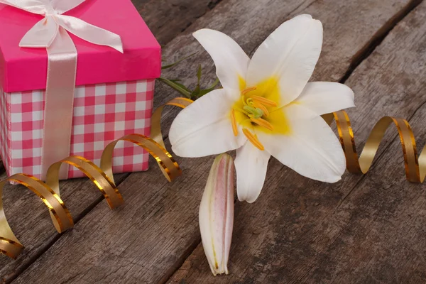 Geschenk-rosa Schachtel und eine weiße Lilienblüte auf dem Tisch — Stockfoto