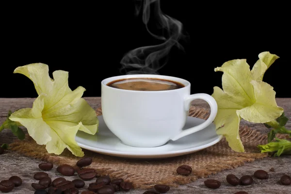 Caffè caldo e fiori di petunia gialli sul tavolo — Foto Stock