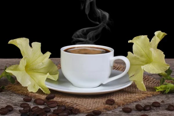 Café caliente y flores de petunia amarillas sobre la mesa —  Fotos de Stock