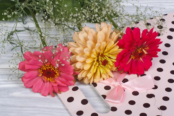 Multi-colored zinnia flowers with gypsophila and gift bag — Stock Photo, Image