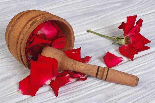 Red rose petals spilled from a wooden mortar — Stock Photo, Image