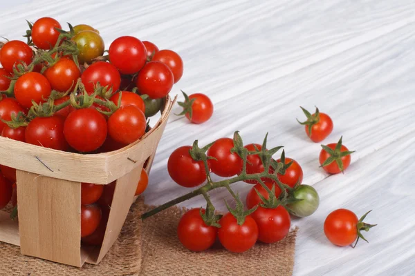 Tomates cereja maduros frescos em um recipiente em uma mesa de madeira — Fotografia de Stock