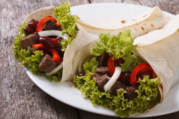 Burrito com carne e legumes e molho na mesa close-up — Fotografia de Stock