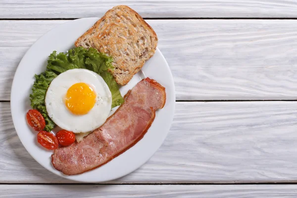 Fried egg with cherry tomatoes and bacon on the table. top view — Stock Photo, Image