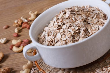 yulaf bir kabın içinde flakes ve tablo fındık üzerinde dağılmış. yakın çekim