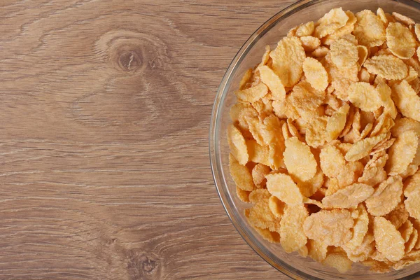 Dry corn flakes in a glass bowl on the table. View from above. — Stock Photo, Image