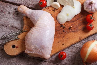 Fresh raw chicken leg on a cutting board.