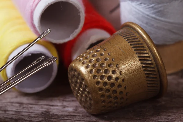 Thimble and needles for sewing closeup on a background thread — Stock Photo, Image