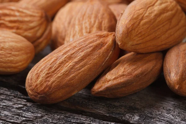 Whole almonds close up on an old wooden table — Stock Photo, Image
