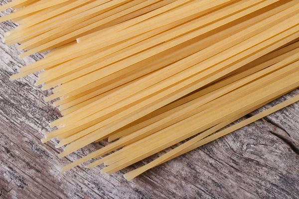 Dry spaghetti on the old wooden table — Stock Photo, Image