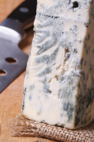 Blue cheese on a kitchen board and knife. vertical macro. — Stock Photo, Image