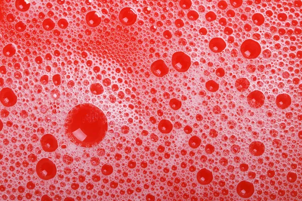 Espuma e bolhas de sabão no fundo vermelho close-up. macro — Fotografia de Stock