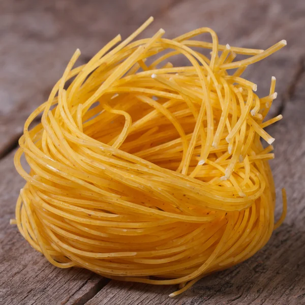 Dry yellow pasta nest close up on an old wooden — Stock Photo, Image