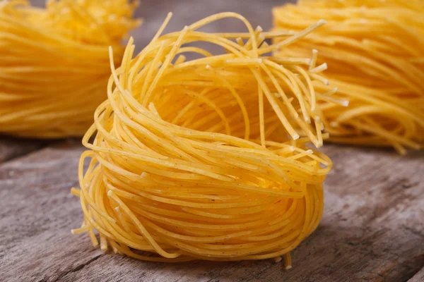 Pasta secca sotto forma di nidi da vicino su un vecchio legno — Foto Stock