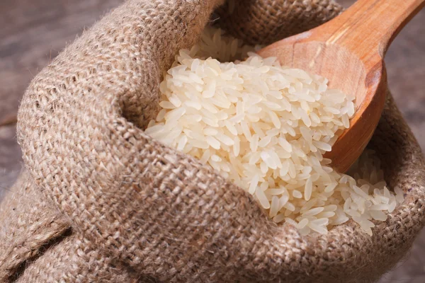 Arroz seco largo en la cuchara de madera macro en el saco —  Fotos de Stock