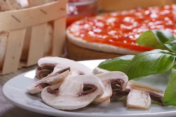 Sliced ??mushrooms and basil for baking pizza closeup on a plate — Stock Photo, Image
