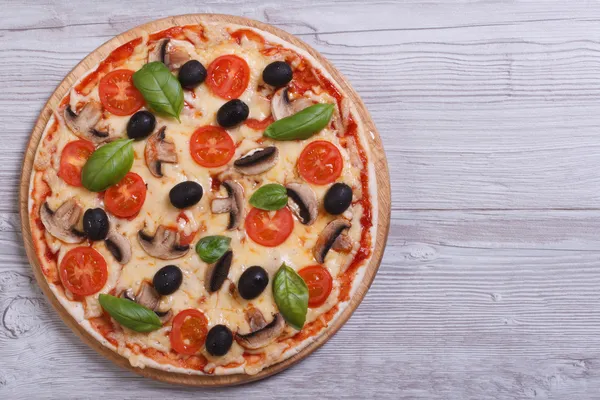 Pizza ai funghi con olive, pomodori e basilico in tavola — Foto Stock