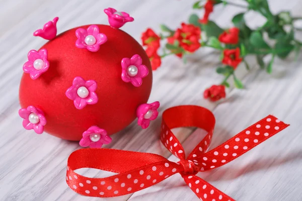 Červené velikonoční vajíčko zdobené růžovými květy s lukem — Stock fotografie
