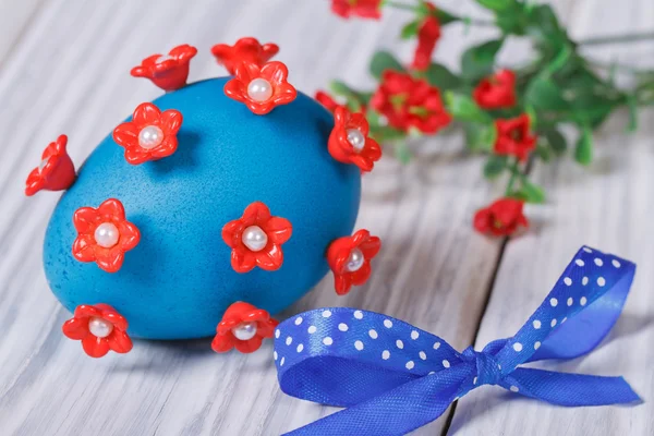 Blue easter egg decorated with red flowers with bow — Stock Photo, Image