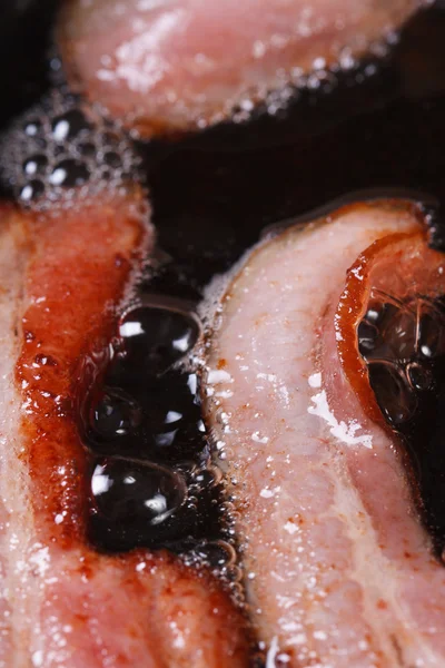 Bacon frying in a pan. closeup. vertical — Stock Photo, Image