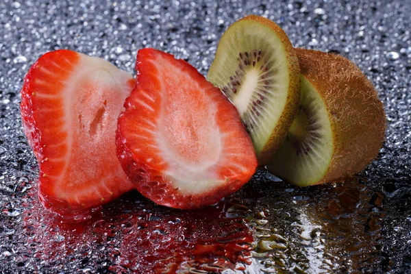 Cortar kiwi y fresas con gotas de agua de cerca —  Fotos de Stock