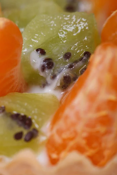 Pieces of kiwi and tangerine slices with cream macro — Stock Photo, Image