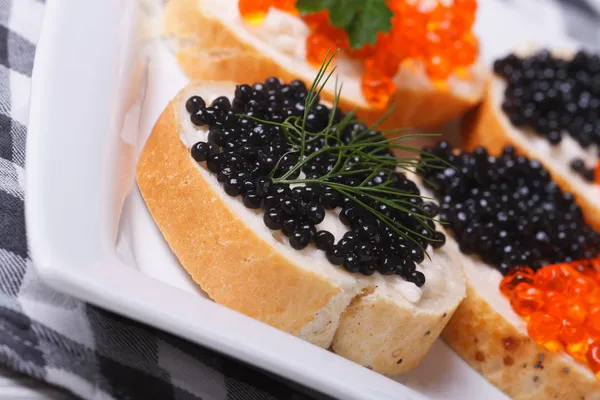 Sándwiches con caviar negro y rojo en un plato macro . — Foto de Stock