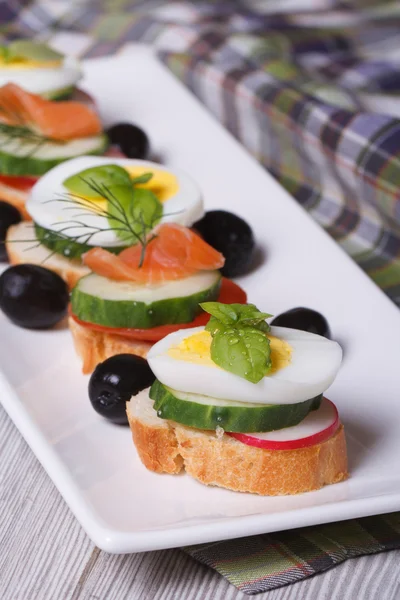 Canape with boiled egg, cucumber, radish, salmon vertical — Stock Photo, Image