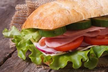 ciabatta sandwich with ham and vegetables macro on table. clipart